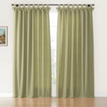 Sage green linen-look tab-top curtains featuring decorative ruffled tops hung on a black rod in a bright room with a hardwood floor and a small framed landscape painting on the wall