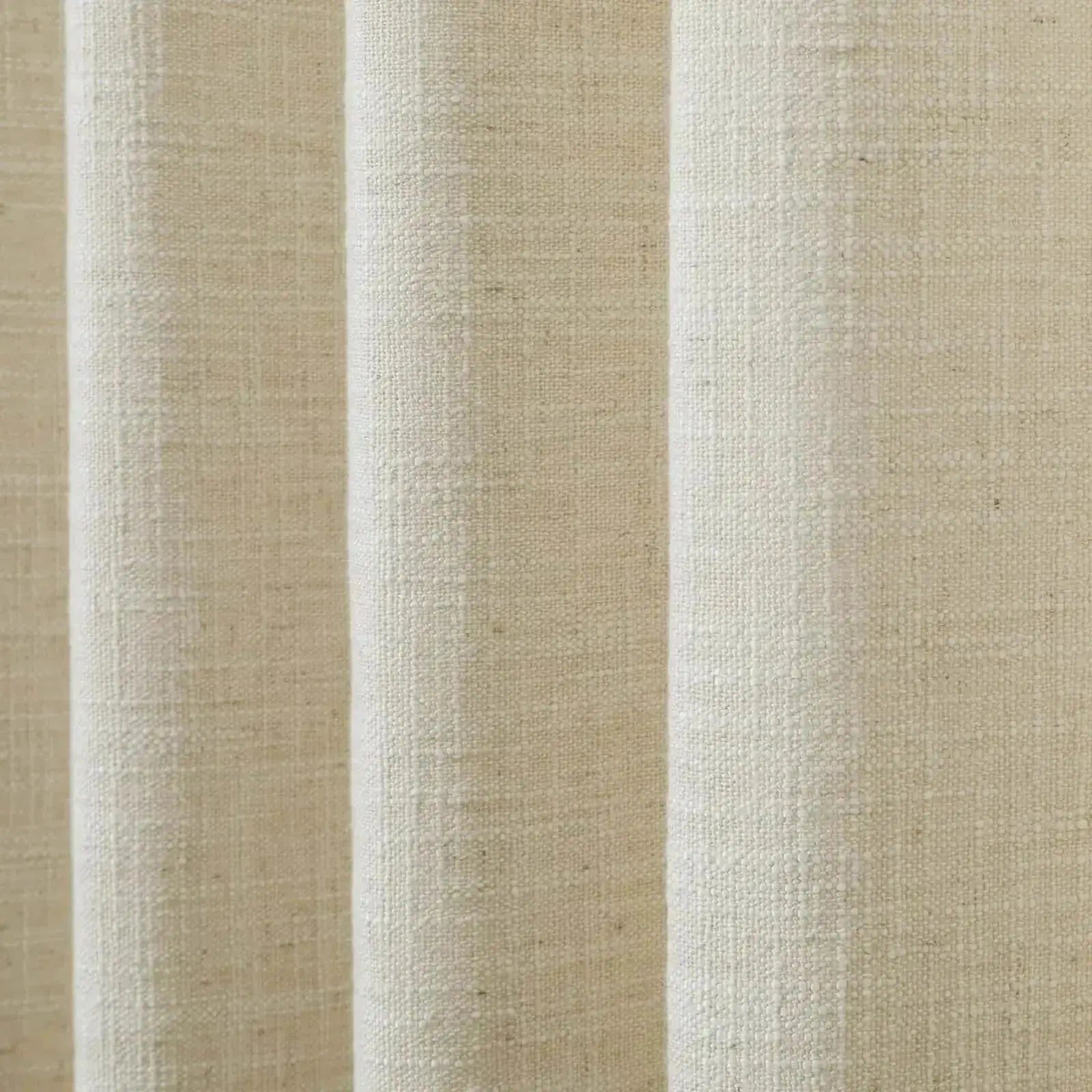 Close-up of oatmeal colored fabric with a coarse woven texture draped in soft vertical folds