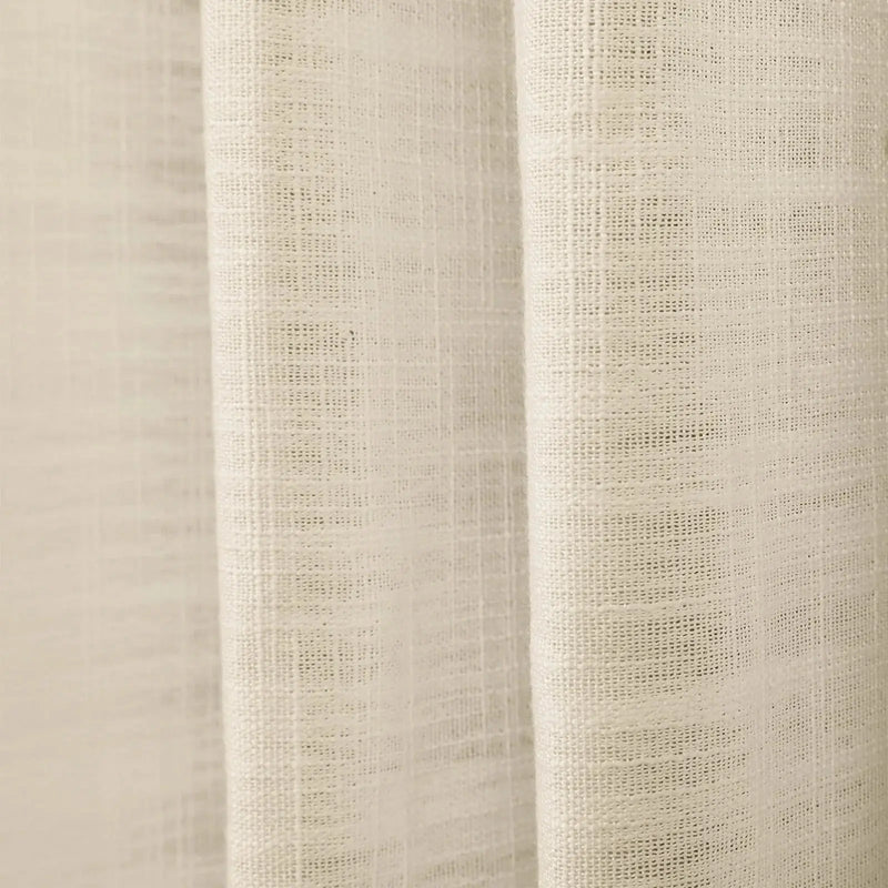 Photograph of light beige textured woven fabric draping in soft vertical folds with a subtle grid weave visible
