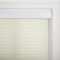 Photograph of a light beige zebra roller Blind with alternating sheer and opaque horizontal stripes, installed within a white window frame featuring classic molding and a visible white pull cord
