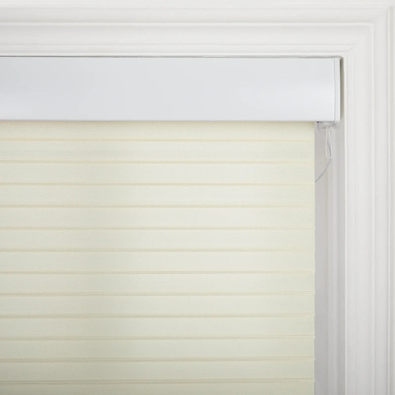 Photograph of a light beige zebra roller Blind with alternating sheer and opaque horizontal stripes, installed within a white window frame featuring classic molding and a visible white pull cord