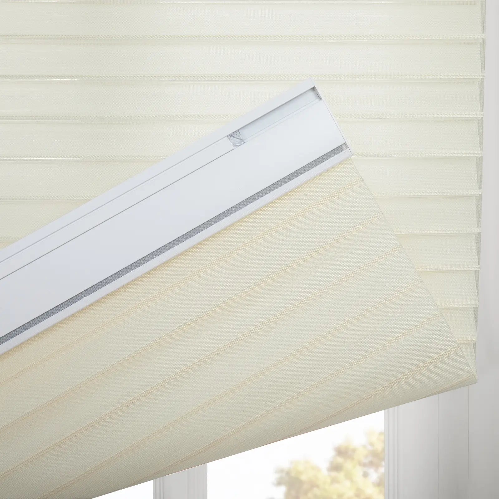 Close-up of a cream sheer horizontal window Blind featuring its alternating striped fabric and white headrail with a glimpse of blurred foliage outside