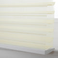 Close-up of cream day-night zebra Blinds in a window featuring alternating translucent and opaque horizontal stripes and a white bottom rail with a subtle 'Light' brand logo