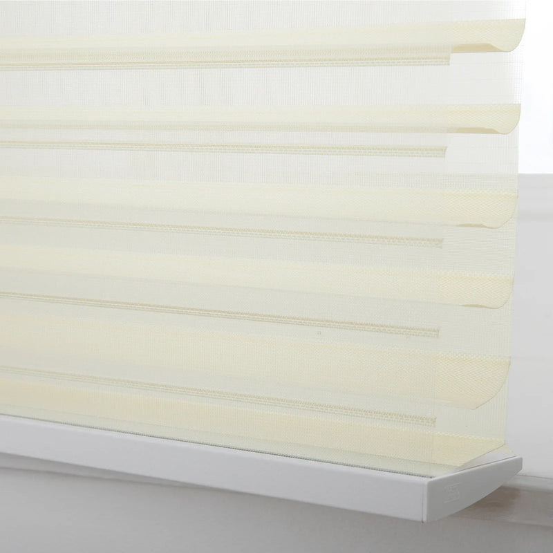 Close-up of cream day-night zebra Blinds in a window featuring alternating translucent and opaque horizontal stripes and a white bottom rail with a subtle 'Light' brand logo
