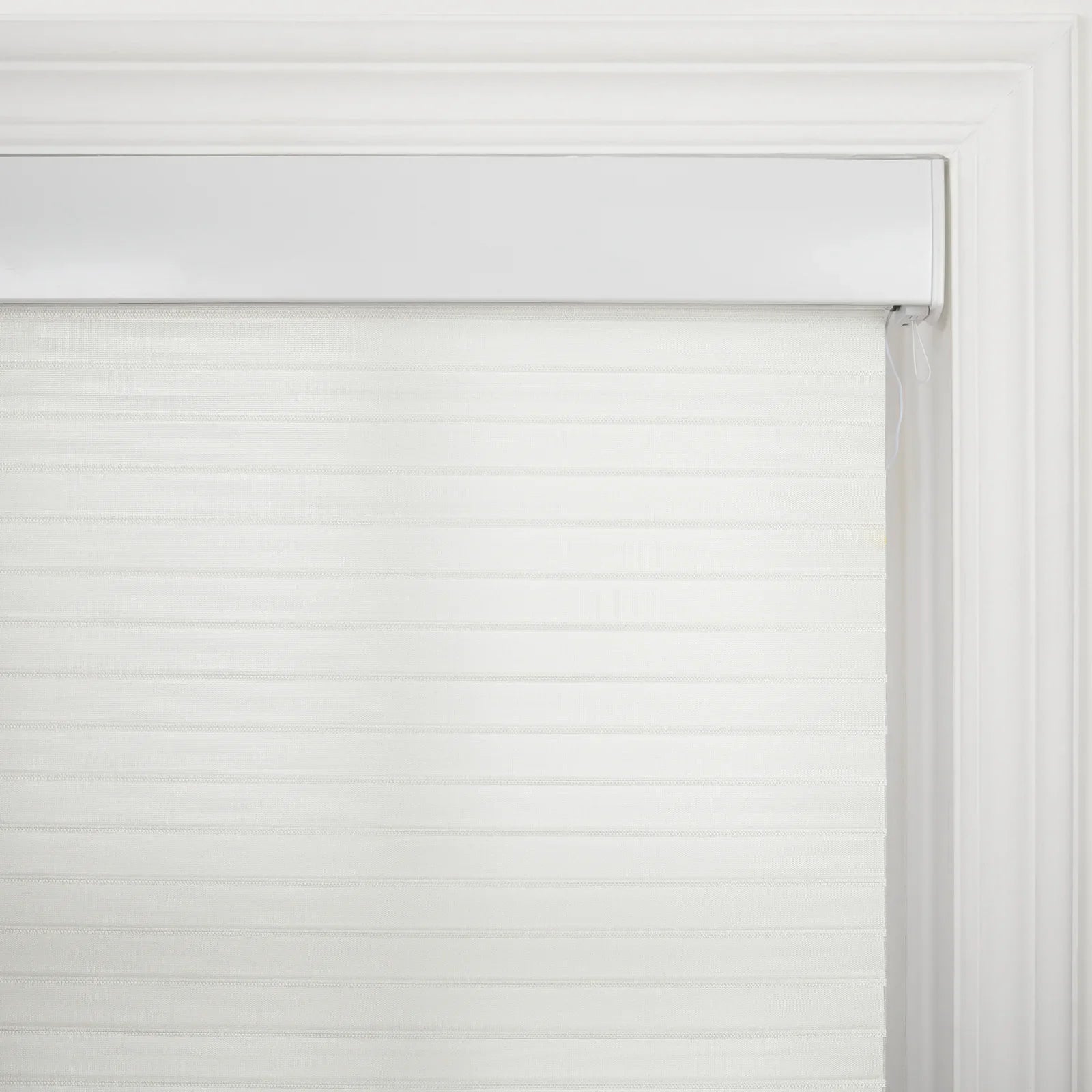 White zebra roller Blind featuring alternating translucent and opaque horizontal bands installed within an ornate white window casing with a visible control cord