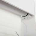Close-up of a white motorized window Blind mechanism with a sheer fabric Blind featuring subtle horizontal textured bands, showing a white power cable connected to the housing and a small white pull cord loop
