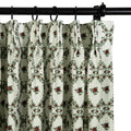Photograph of a pleated cream curtain featuring a repeating pattern of deep red roses and green leaves hanging from a black rod with rings