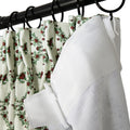 Close-up of pleated white curtains featuring a vibrant red rose and green leaf pattern, alongside a textured white liner, all suspended from a black curtain rod by black rings and white plastic hooks
