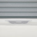 Close-up of gray textured cellular pleated window Blinds with a white frame and an integrated gray adjustment handle