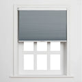 A white-framed window featuring a partially lowered grey cellular Blind above six blank white panes