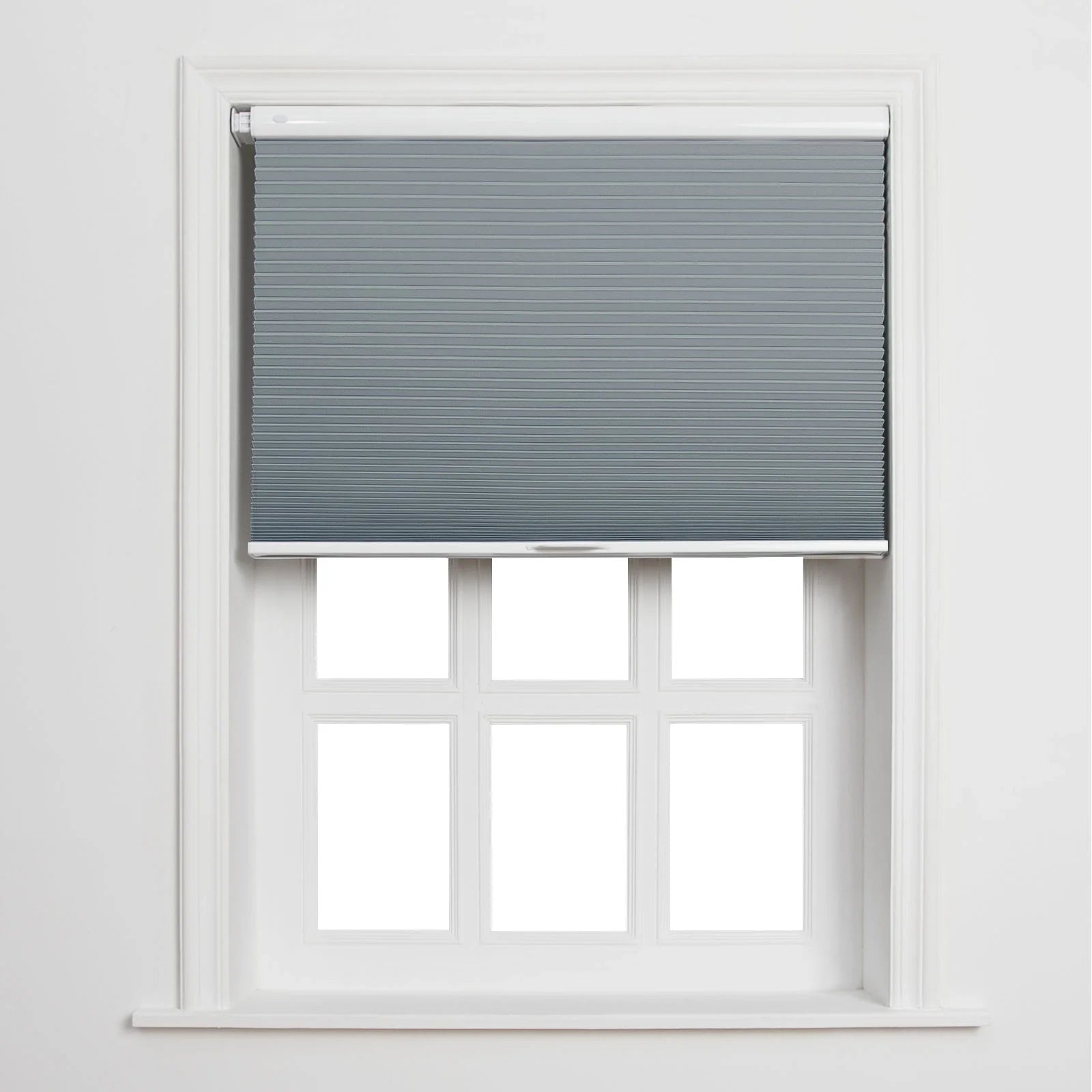 A white-framed window featuring a partially lowered grey cellular Blind above six blank white panes