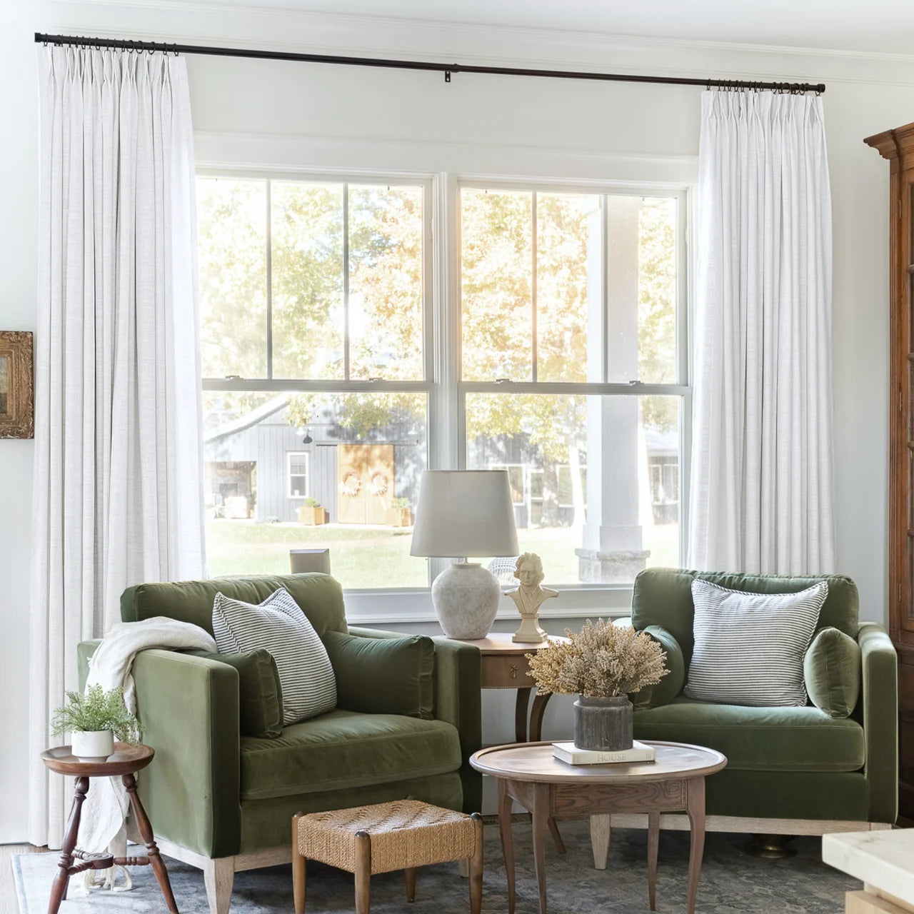 Snow White Liz Linen Pleated Curtains framing a green sofa beneath a wide sunlit window