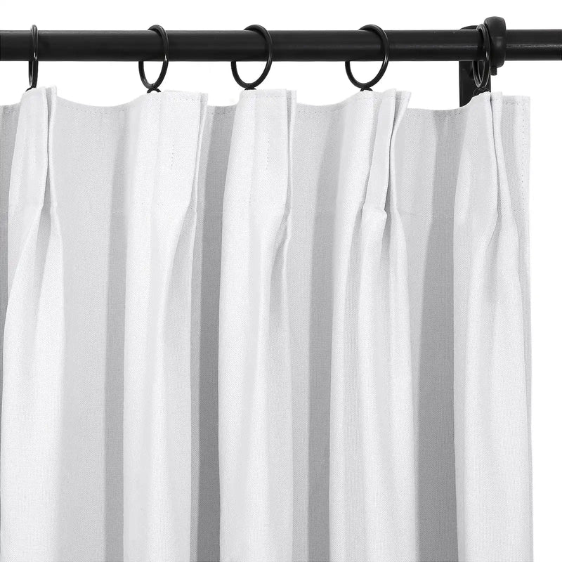 White textured pinch-pleat curtains hanging on a black metal curtain rod with black rings
