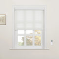 A white layered Roman Blind partially lowered over a white multi-paned window with a wall-mounted remote control on the wall