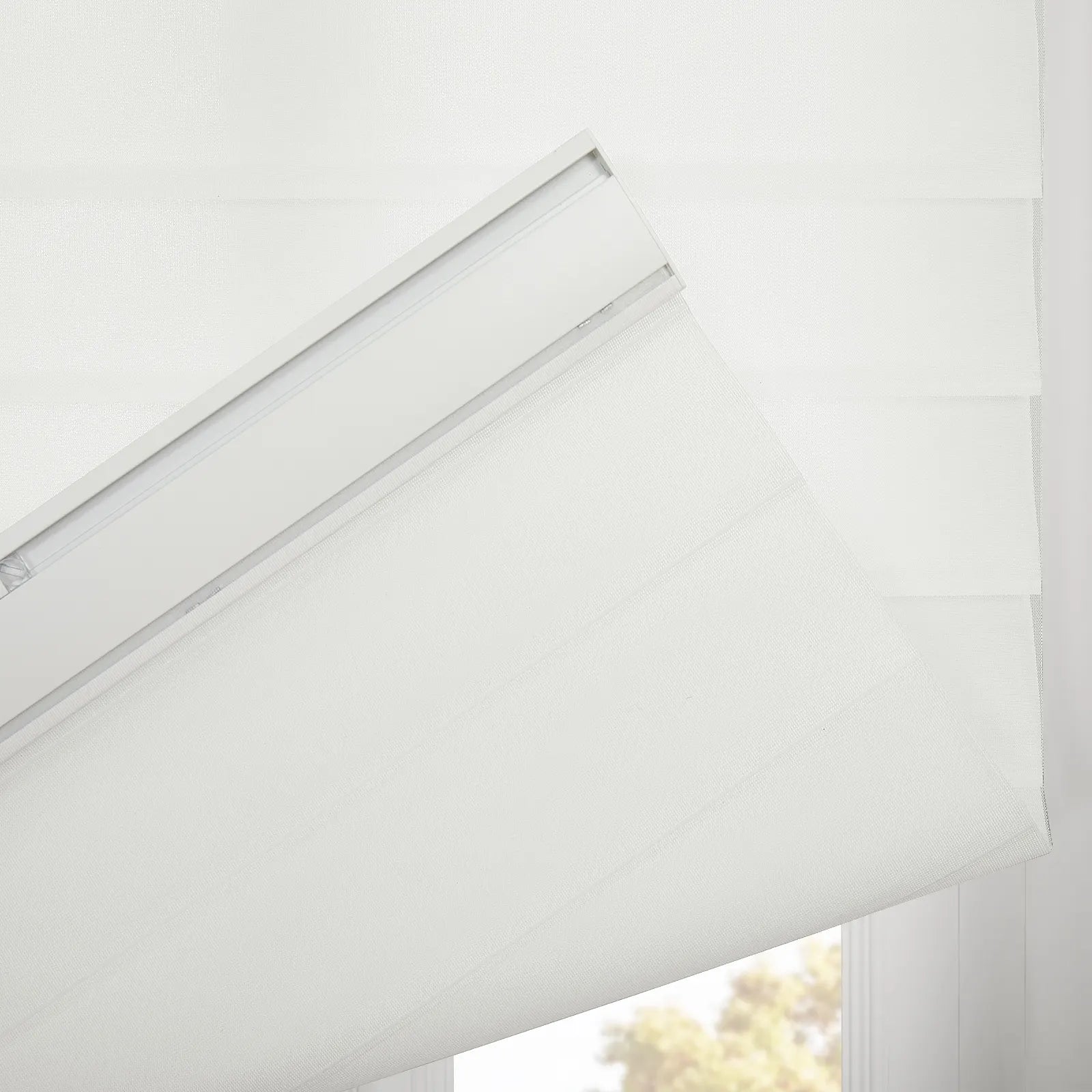 Photograph of a white zebra roller Blind featuring horizontal sheer and solid textured fabric with a visible white headrail and blurred green foliage visible through the bottom