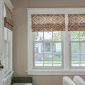 Photograph of an interior window with beige and brown damask patterned Roman shades looking out to a residential street with a white house, an American flag, and a Sherri Caldwell yard sign