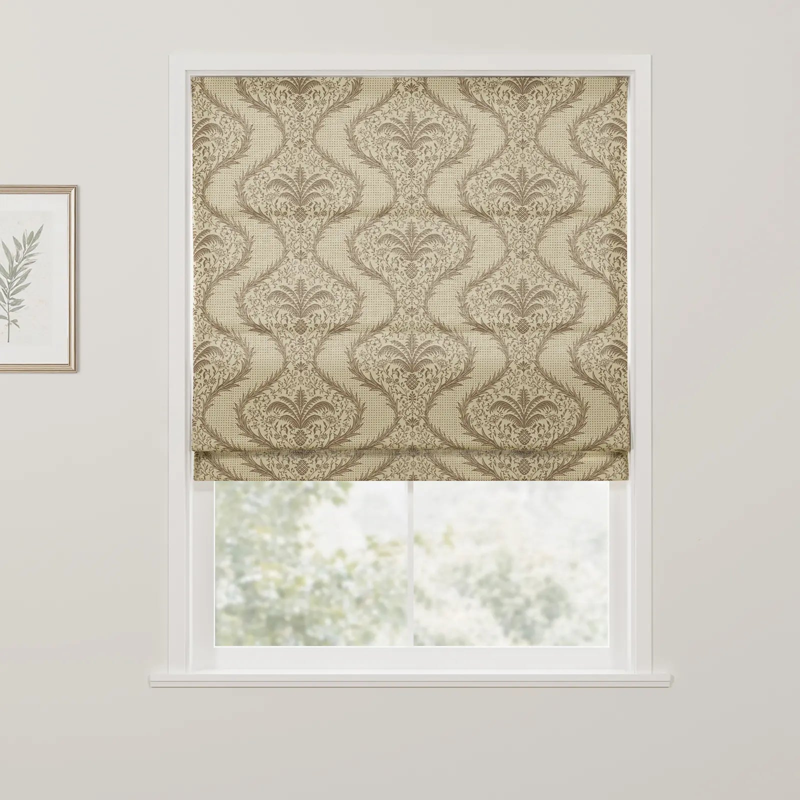A classic beige and brown Roman blind featuring an elaborate damask pattern with stylized fern and pineapple-like motifs partially covering a window looking out to blurred greenery