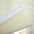 Layered cream and sheer fabric zebra Blind with a white headrail partially open revealing blurred outdoor trees