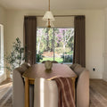 Taupe Grey Liz Linen Pleated Curtains in a bay-window dining nook with upholstered chairs and garden view