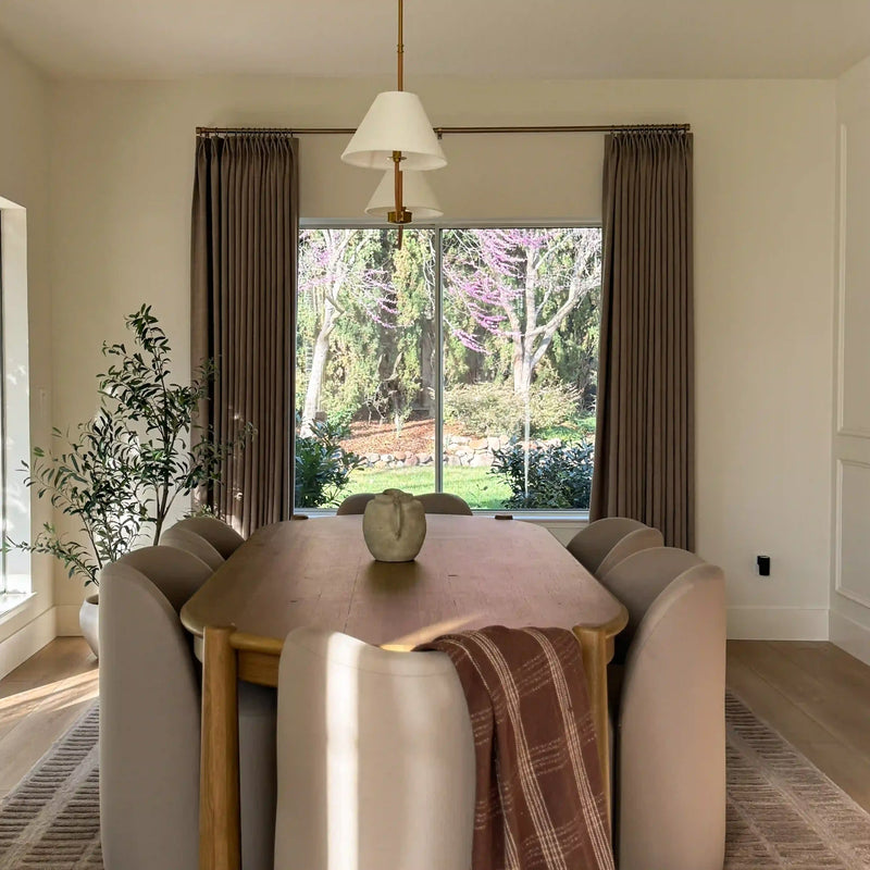 Taupe Grey Liz Linen Pleated Curtains in a bay-window dining nook with upholstered chairs and garden view
