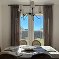 Taupe Grey Liz Linen Pleated Curtains around patio doors behind a set dining table and black chandelier