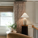 Sara Le x TWOPAGES Vintage Printed Linen Pleated Curtains - Travertine floral curtains beside a bright landing window, ceramic lamp and leafy plant