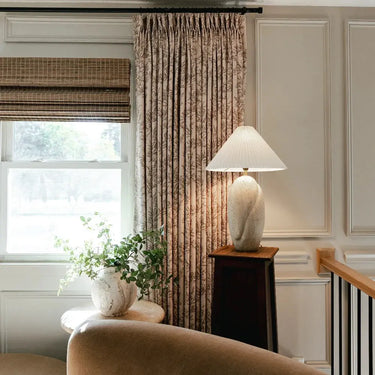 Sara Le x TWOPAGES Vintage Printed Linen Pleated Curtains - Travertine floral curtains beside a bright landing window, ceramic lamp and leafy plant