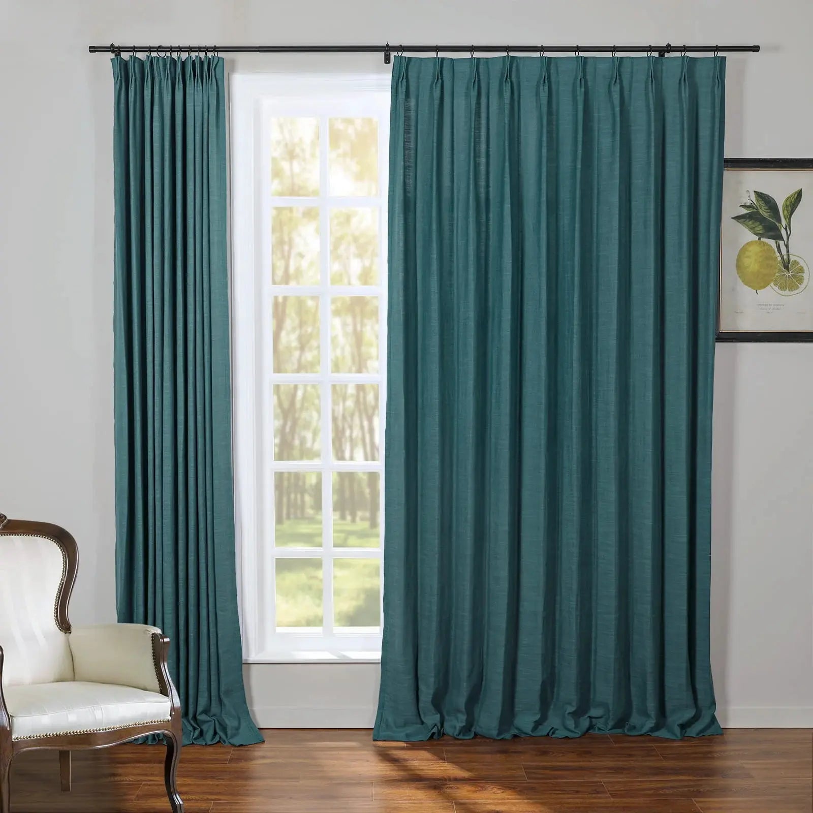 Teal linen pleated curtains on a black rod frame a multi-pane window with a bright green outdoor view beside a classic white tufted armchair and a framed lemon botanical print
