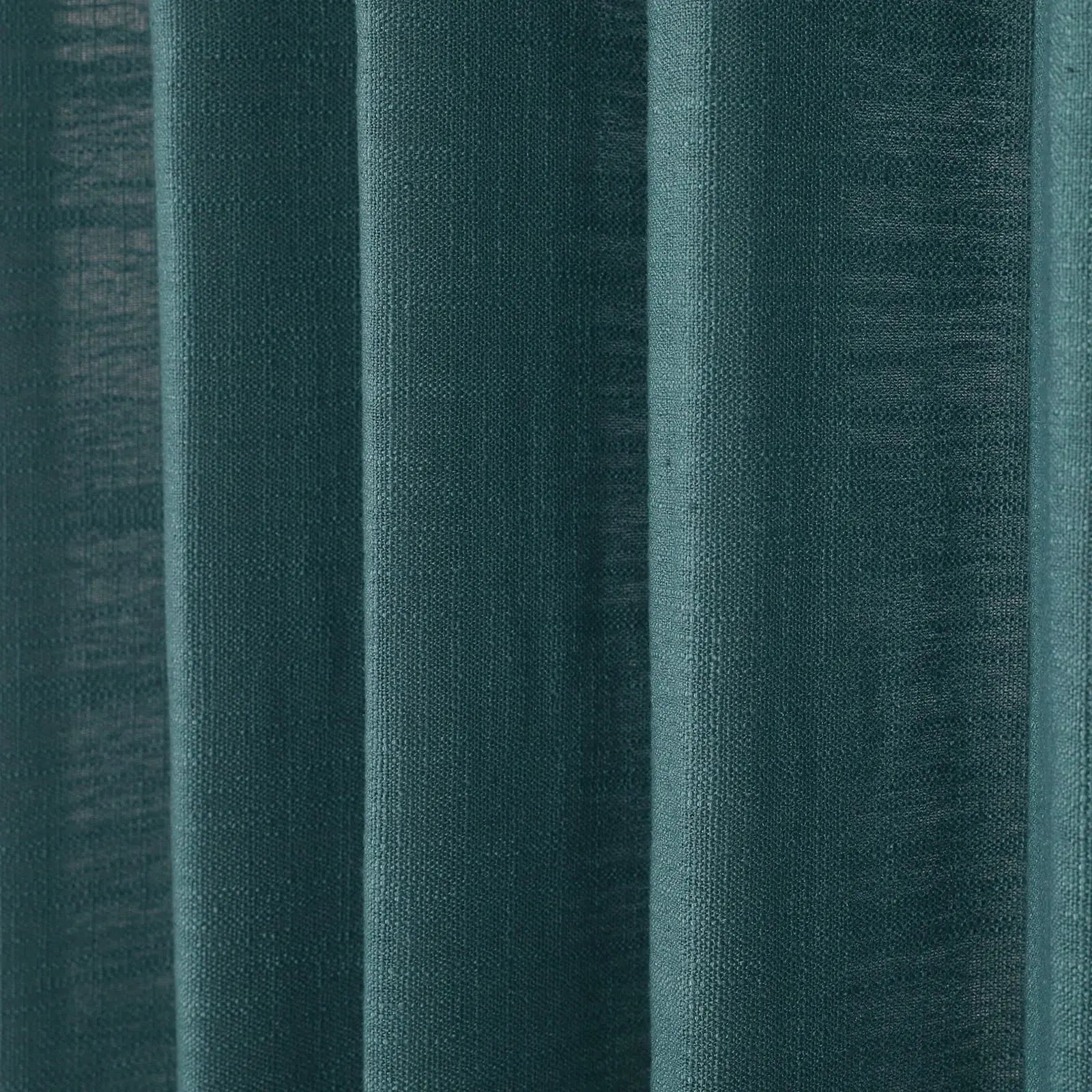 A close-up of deep teal fabric curtains featuring prominent vertical folds and a visible woven texture