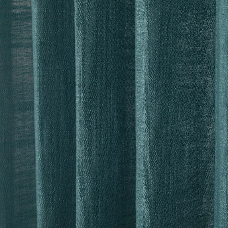 A close-up of deep teal fabric curtains featuring prominent vertical folds and a visible woven texture