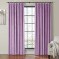 Velvet lilac pinch pleat curtains frame a large grid window, revealing a beige armchair with a white fringed throw and modern gray tree artwork on a light wall