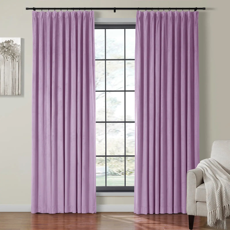 Velvet lilac pinch pleat curtains frame a large grid window, revealing a beige armchair with a white fringed throw and modern gray tree artwork on a light wall