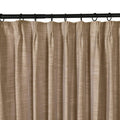 Photograph of a tan textured linen-look pleated curtain hanging from a black rod with rings