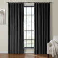 Black velvet pleated curtains hang on a dark rod framing a window in a modern room decorated with abstract gray tree artwork and a beige armchair