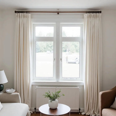 Kyla Lightweight Faux Linen Pleated Curtains - Warm White curtains framing a bright living-room window above a radiator and round table