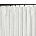 White textured linen blend curtain with subtle pleats hanging from black metal rings on a sleek black curtain rod