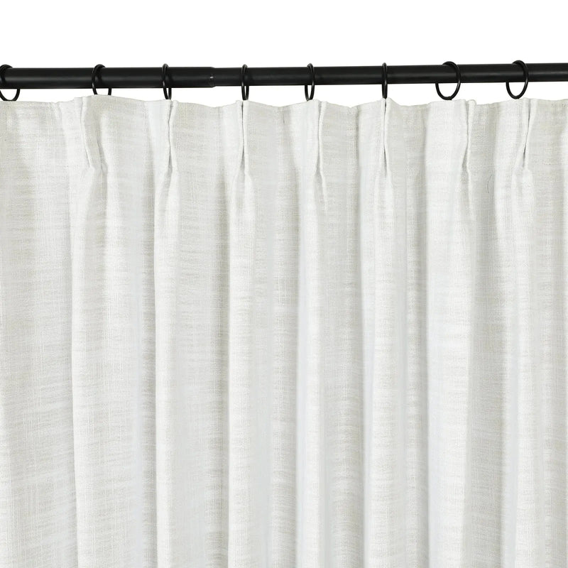 White textured linen blend curtain with subtle pleats hanging from black metal rings on a sleek black curtain rod