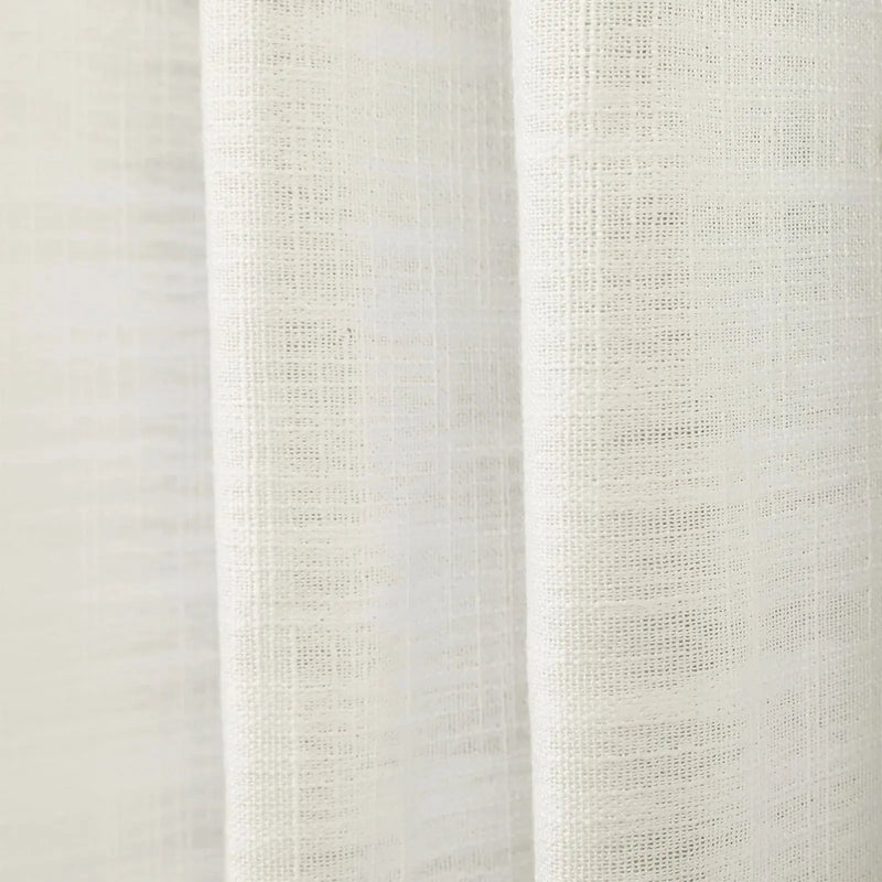 Photograph of a cream-colored sheer woven fabric showing a subtle grid texture and gentle vertical drapes