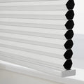 White cellular Blinds with textured pleated fabric and visible black honeycomb cells on a sleek silver bottom rail resting on a white window sill