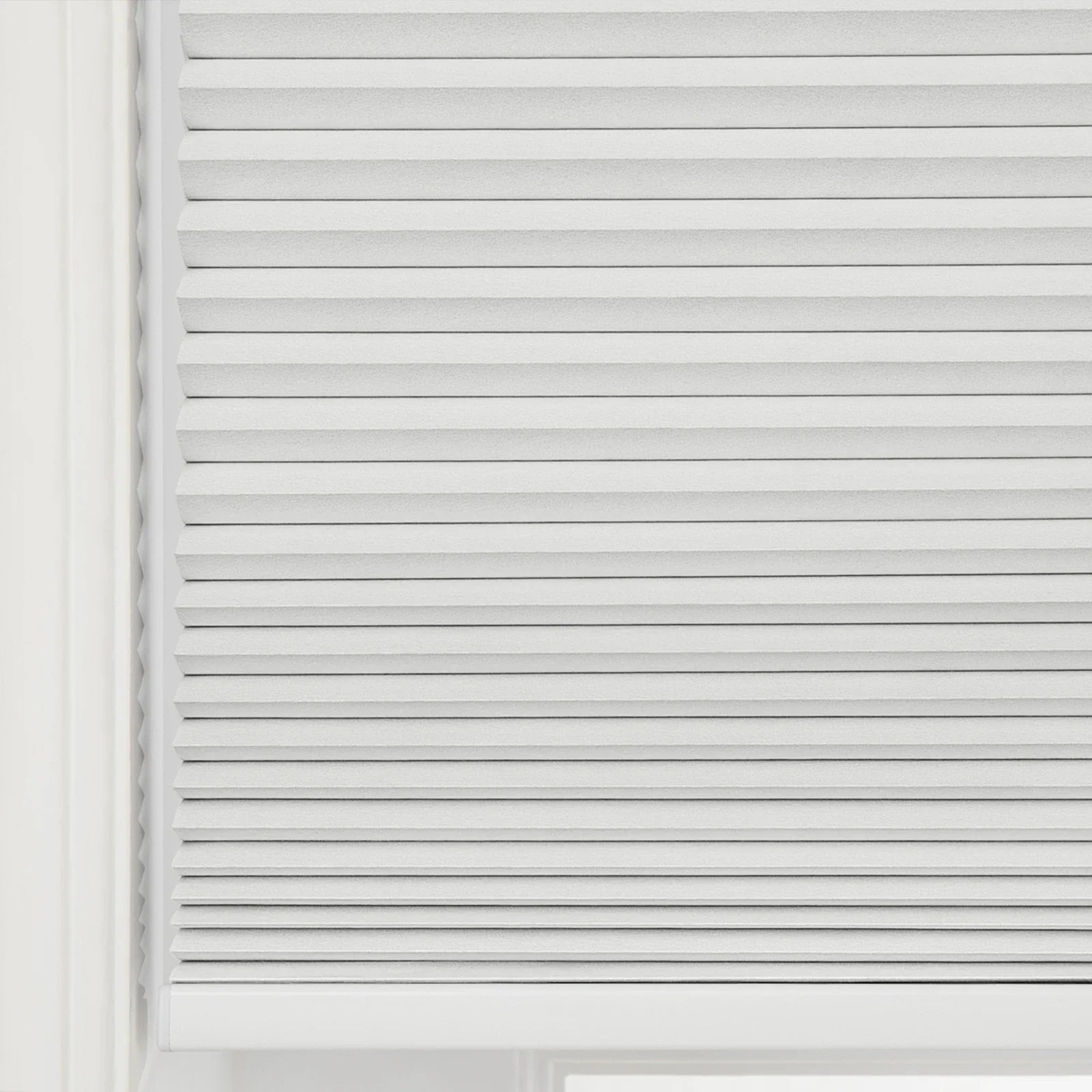 Photograph of light gray pleated cellular window Blinds covering a window, showcasing their textured fabric and horizontal folds