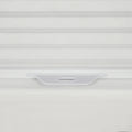 Detailed photograph of a white pleated cellular window Blind showcasing its subtle fabric texture and an integrated light grey plastic bottom rail handle for cordless operation