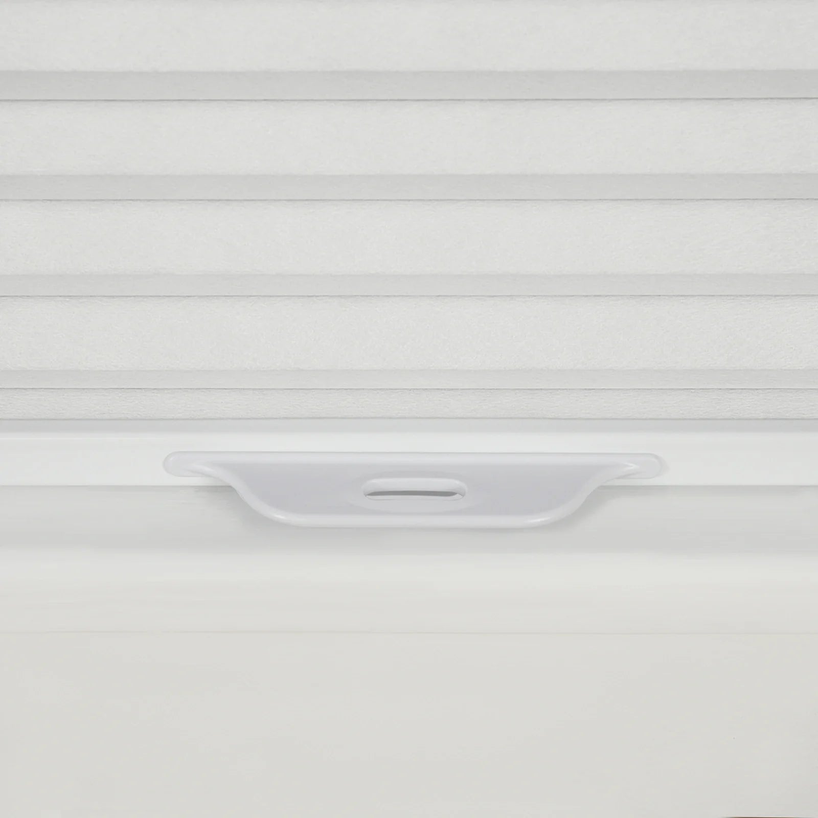 Detailed photograph of a white pleated cellular window Blind showcasing its subtle fabric texture and an integrated light grey plastic bottom rail handle for cordless operation