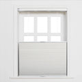 A white paneled window in an interior room featuring light grey top-down bottom-up cellular Blinds with sheer white pull strings and bright light through the upper panes