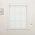 Photograph of an interior window featuring white tiered Roman Blinds, white decorative trim, a subtle framed botanical print to the left, and a white wall-mounted remote control to the right