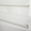White layered roller Blind with alternating sheer and opaque textured fabric partially unrolled showing the bottom bar and end cap