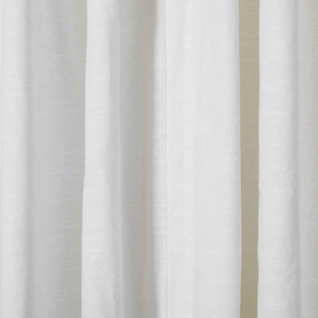 Close-up of white linen curtains showcasing a subtle woven texture soft vertical folds and gentle ambient lighting