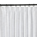 Photograph of white subtly textured curtains with a pleated header hanging on a black metal rod with rings