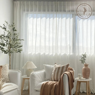 Joy Pure Linen Pleated Voile Curtains - White voile curtains softly filtering daylight in a calm sitting room with layered cushions
