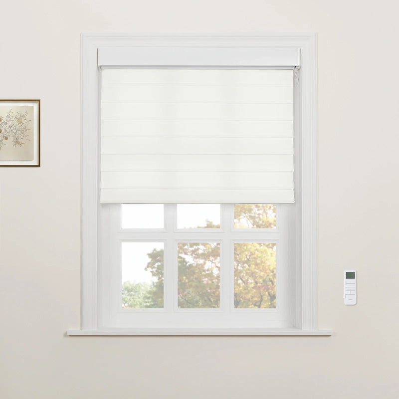 A room featuring a white framed window with partially lowered white Roman Blinds, showing autumn trees outside, complemented by a wall-mounted white remote control and a framed botanical art print