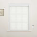 A minimalist room featuring a window with modern white layered zebra Blinds, an elegant white trimmed frame, a small framed botanical print, and a wall-mounted smart remote control